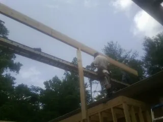 Carpenter setting a ridge beam over a new addition frame — Ice Dam Removal by Roofing Brothers in Conroe