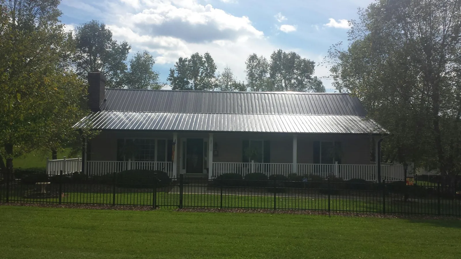 Gray metal roof on a brick ranch with a full width front porch — Gutter Guard Installation work by our crew in Conroe