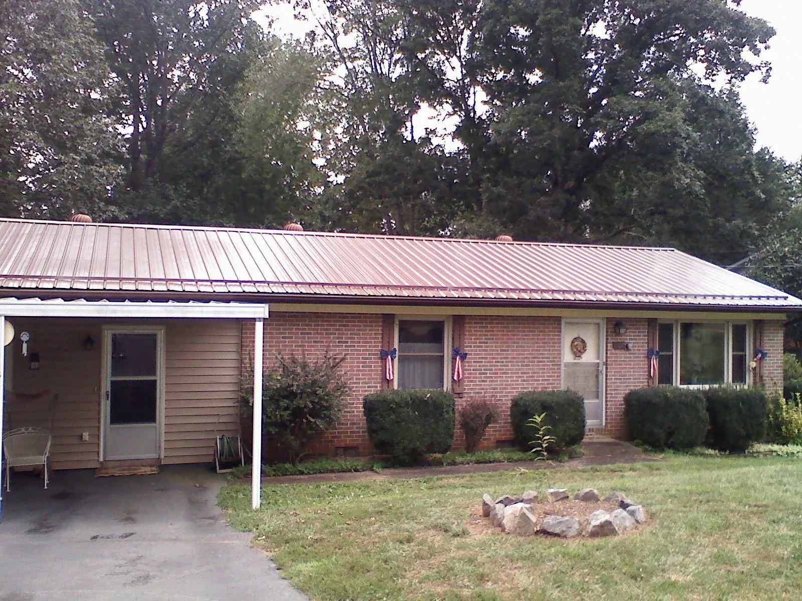 Bronze metal roof and carport on a brick ranch home — Roof Repair work by our crew in Conroe